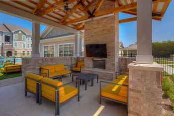 a covered patio with a fireplace and yellow couches